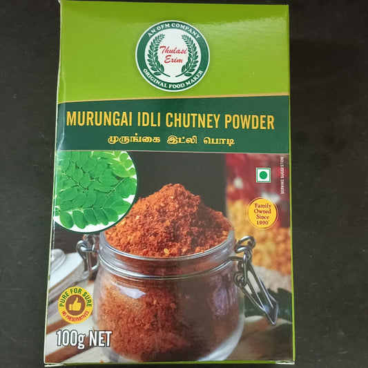 Murungai Idly Chutney Powder pouch with soft idlis, sesame oil, and drumstick leaves on banana leaf background