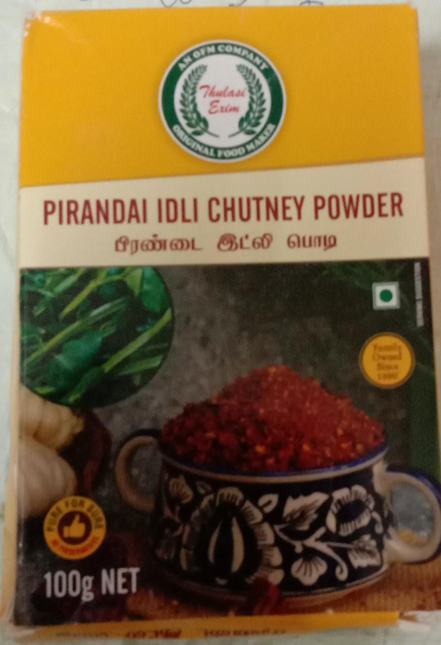 Pirandai Idli Chutney Powder pouch with soft idlis, sesame oil, and fresh pirandai (Adamant Creeper) stems arranged on a banana leaf background