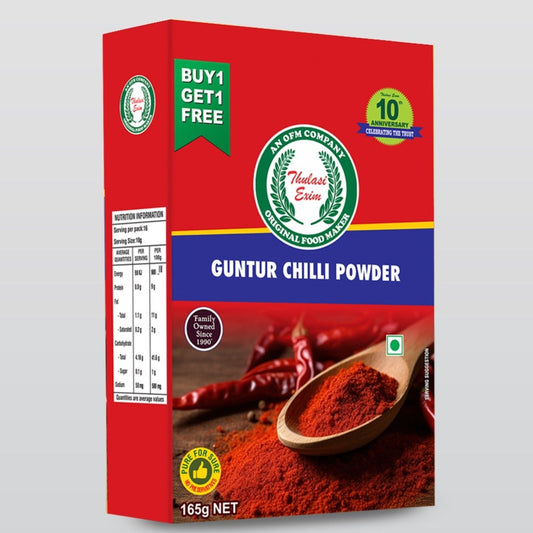 Thulasi_Chilli_Powder_in_kraft_pouch_with_dried_red_chillies_basil_leaves_and_brass_spice_spoon_on_a_banana_leaf_background